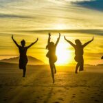 silhouettes of women running on a beach at sunset