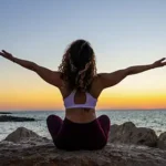 woman sitting on rocks raising both arms